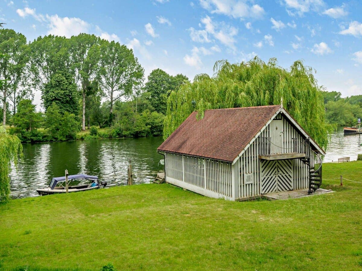 The garden running down to the River Thames, with a willow and boathouse.